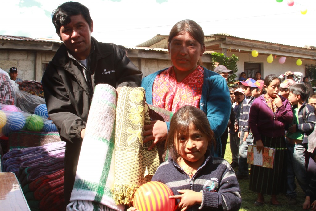 A girl smiles with her new gifts in hand from the Christmas party at project