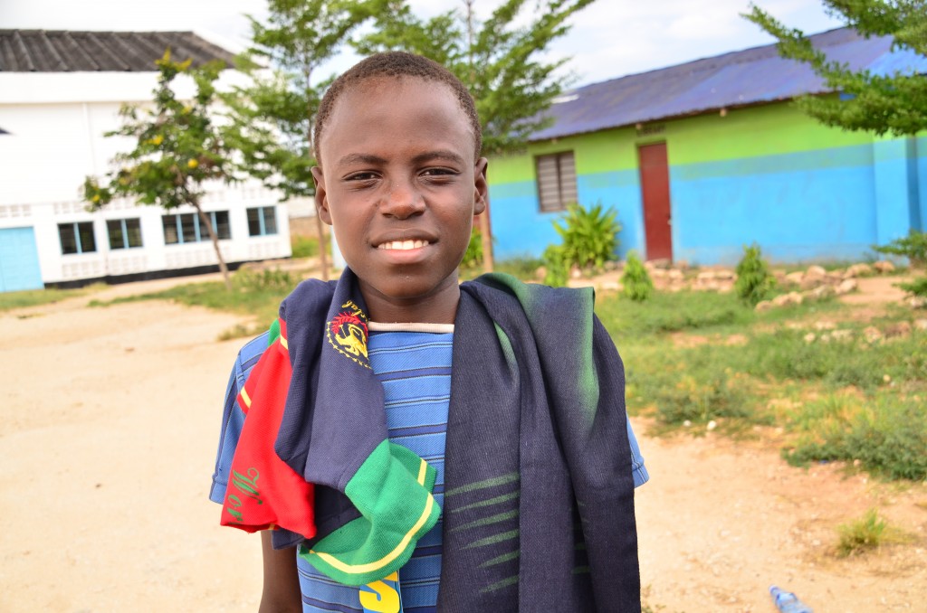 A boy smiles in a close-up with his new clothes on his shoulders