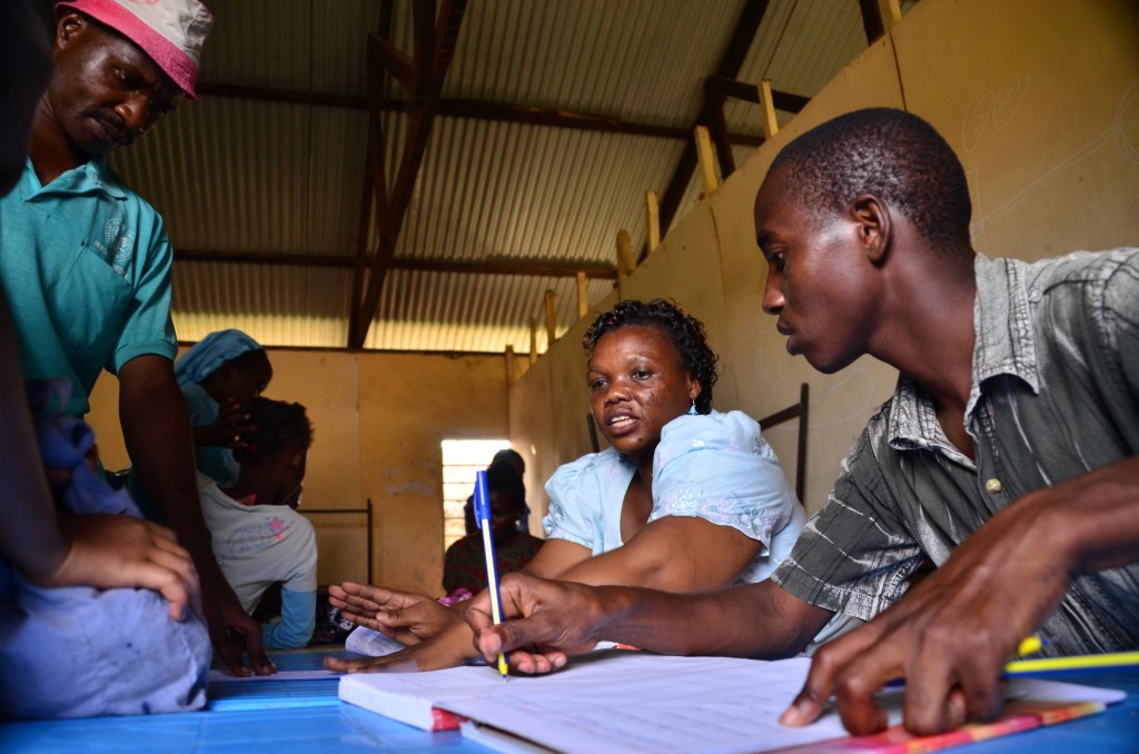 Project staff workers sit at a table together with one writing in a notebook