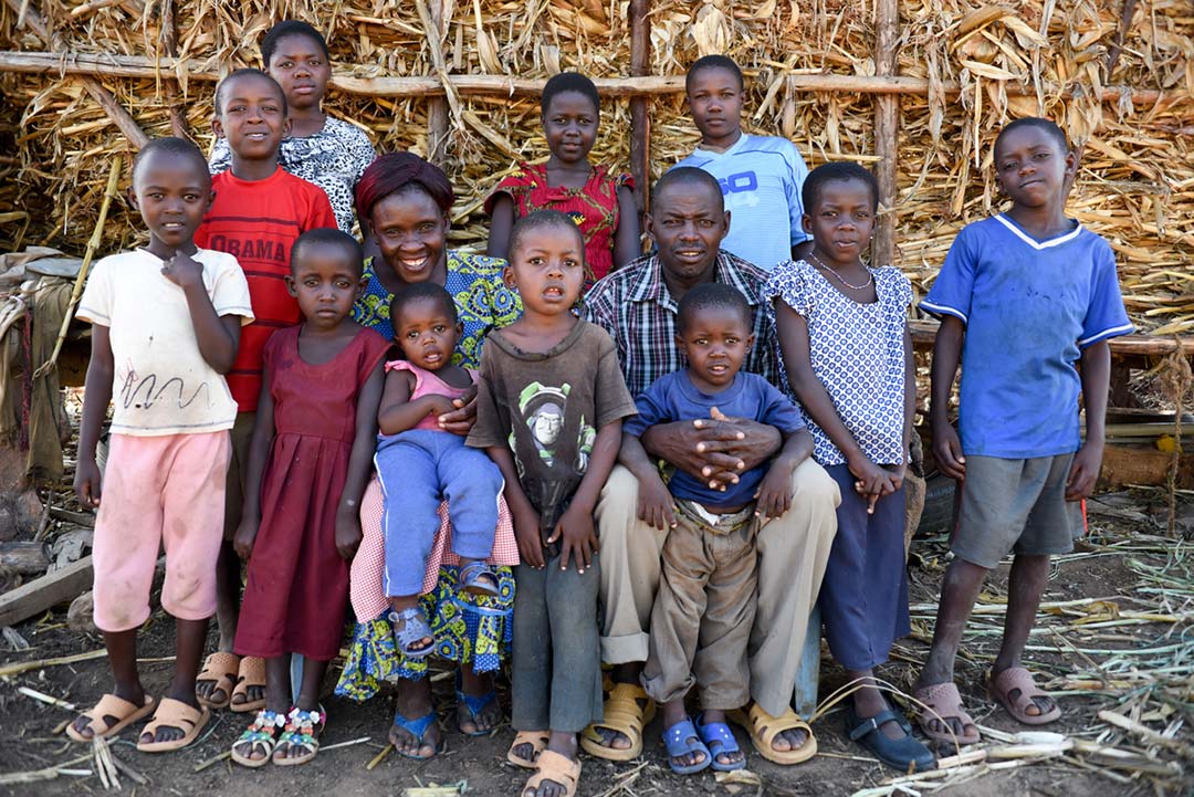 Mother and father and eleven children sit in front of a wagon full of hey.