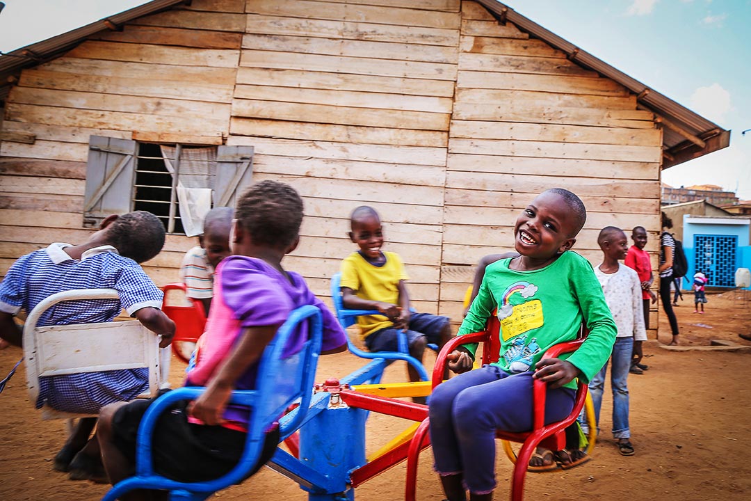 A group of children ride on a merry-go-round in front of their Compassion centre.