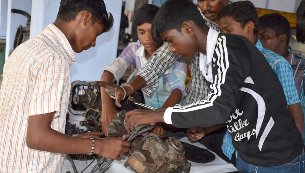 Indian teenagers work on a small motor.