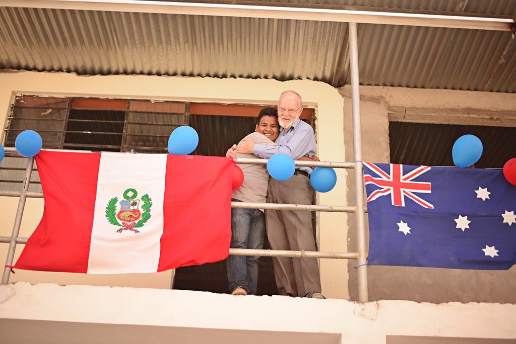 Andrews and his sponsor stand on a balcony and give eachother a hug.