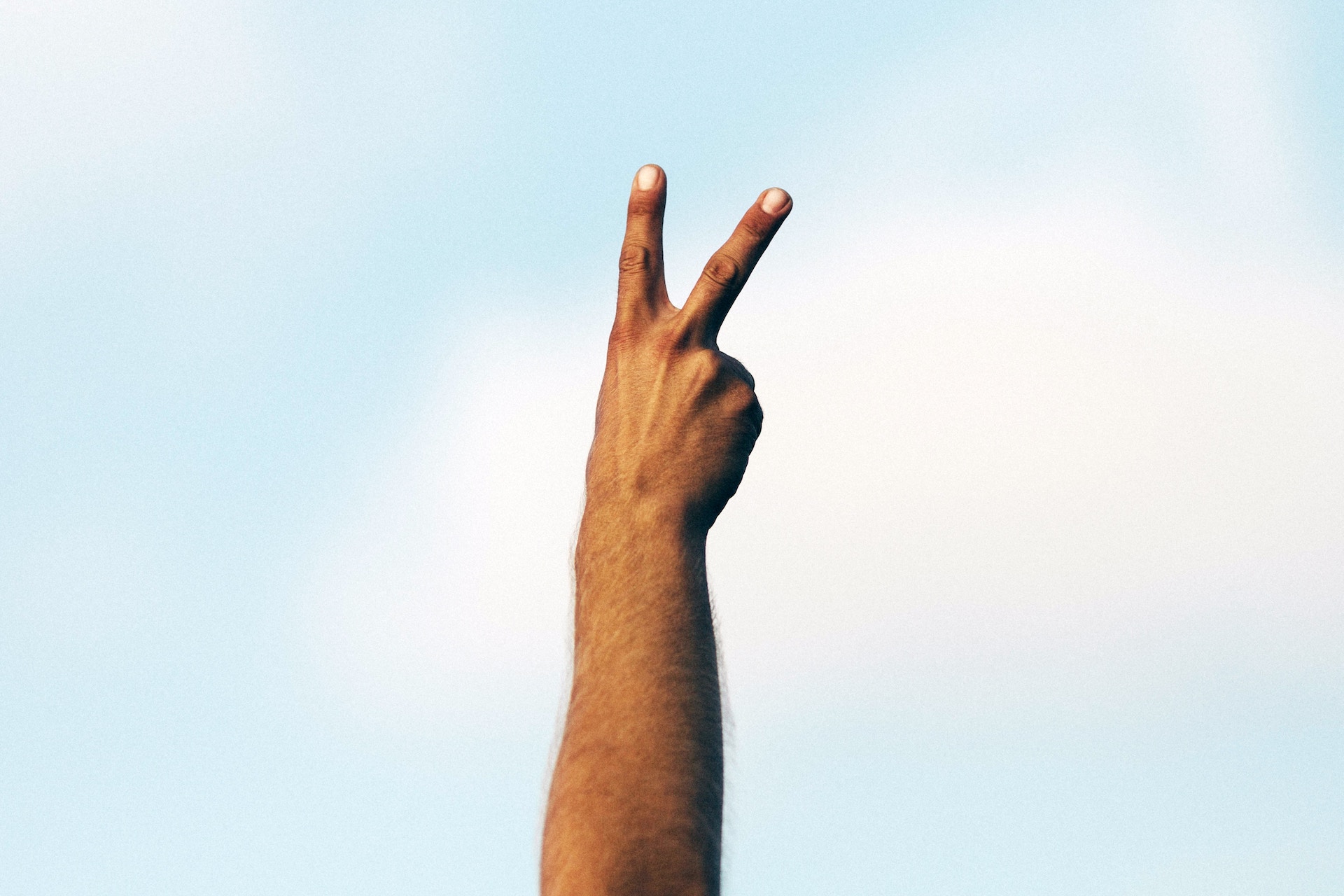 A hand holding up a peace sign to the sky.