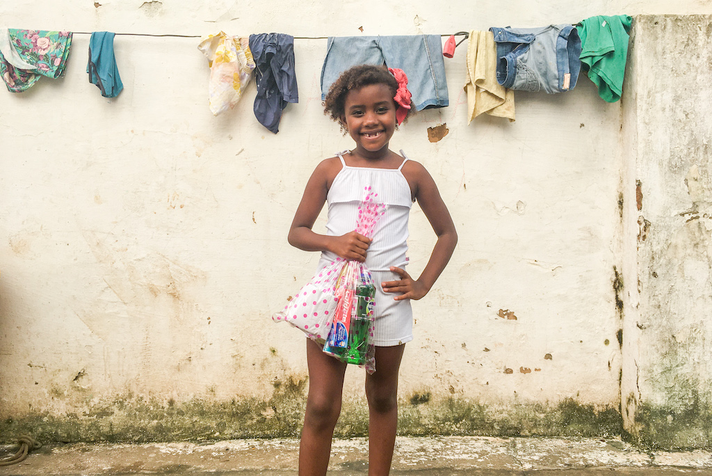A girl in a white dress holds a hygiene kit.