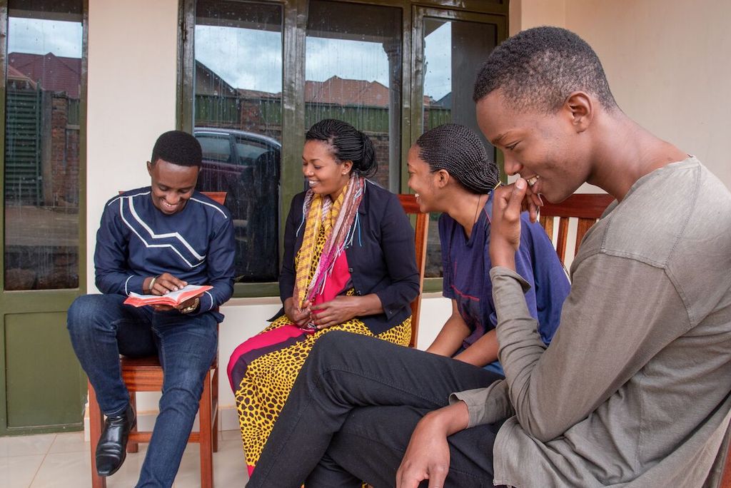 Christian, his aunt Pascasie and his cousins Cynthia and Mugisha sit on the porch together.