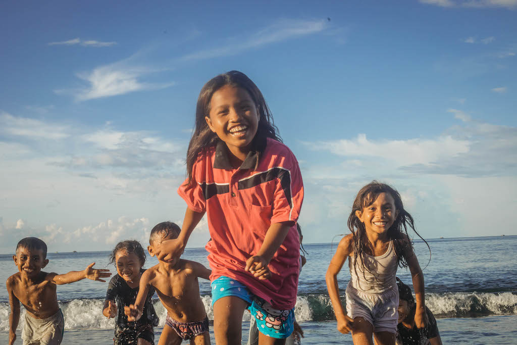 Children run on a beach in Indonesia.